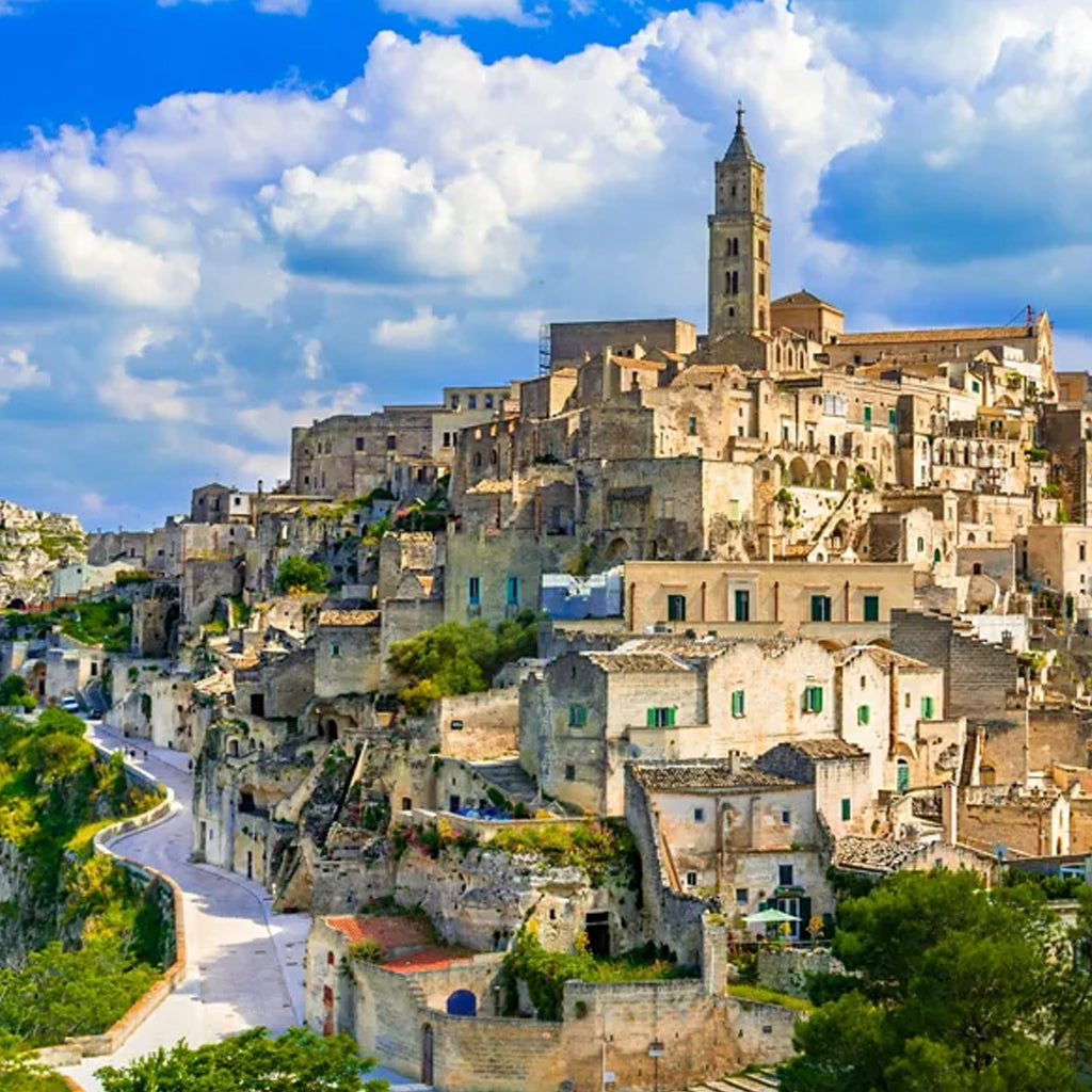 Panoramic view of the ancient stone Sassi di Matera in Basilicata, Italy, showing the historic cave dwellings and cathedral under a clear blue sky.