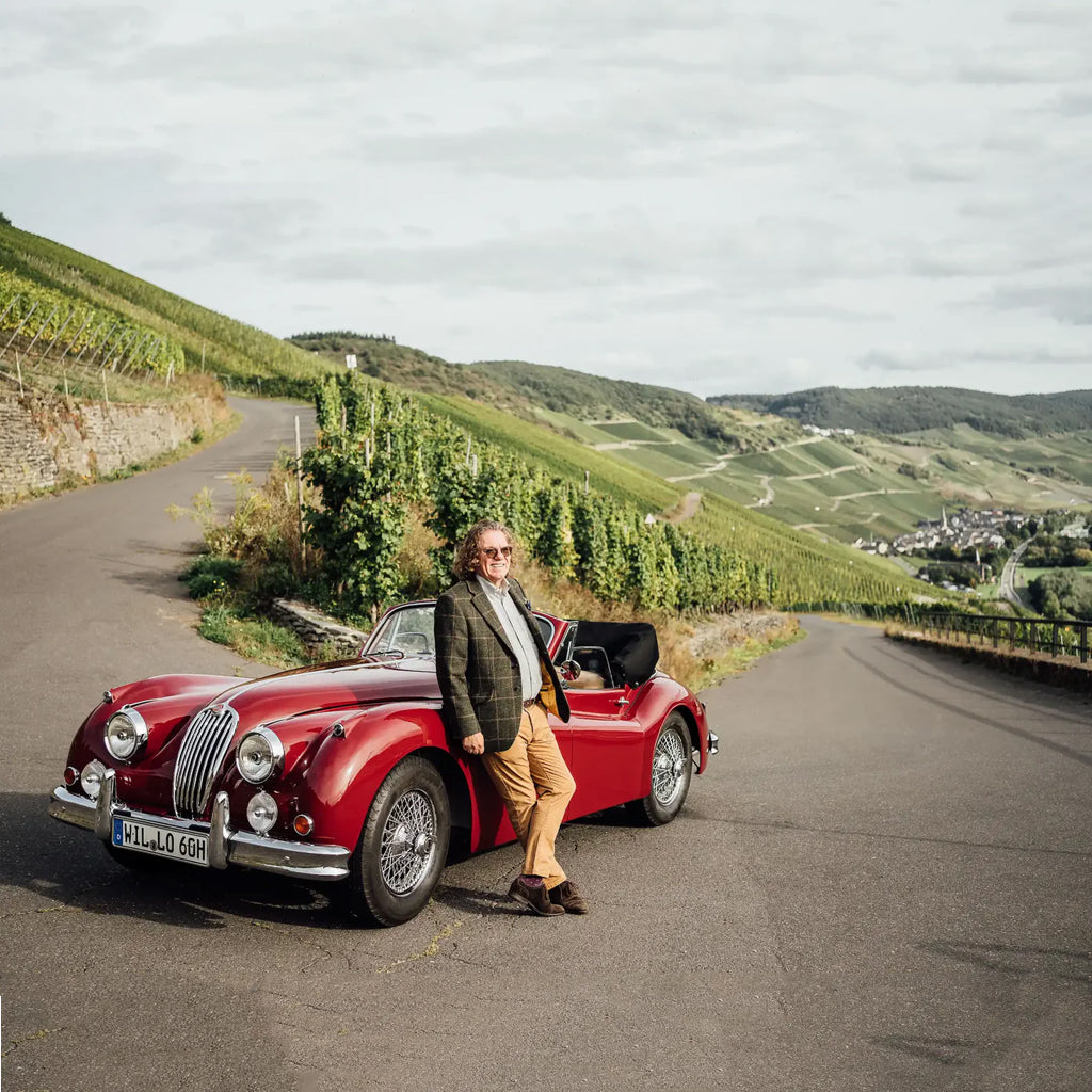 Ernie Loosen stood next to an open top red sports car on the winding road out of Bernkastel Kues