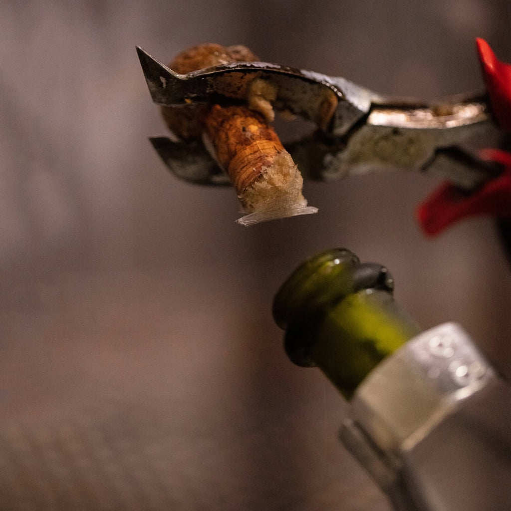 Close up image showing the traditional disgorging method of a Champagne Ruinart Bottle