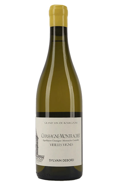 A bottle of Sylvain Debord Chassagne-Montrachet Vieilles Vignes Grand Vin de Bourgogne white wine, featuring an olive green glass bottle with a pale yellow cork and a white label.
