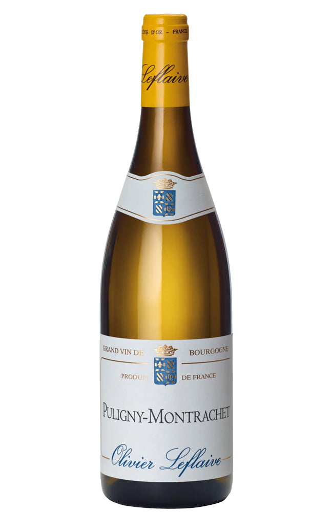 A bottle of Olivier Leflaive Puligny-Montrachet Grand Vin Blanc de Blancs, featuring a gold foil top, a white label with blue and gold details, and a dark green glass base, set against a plain white background.